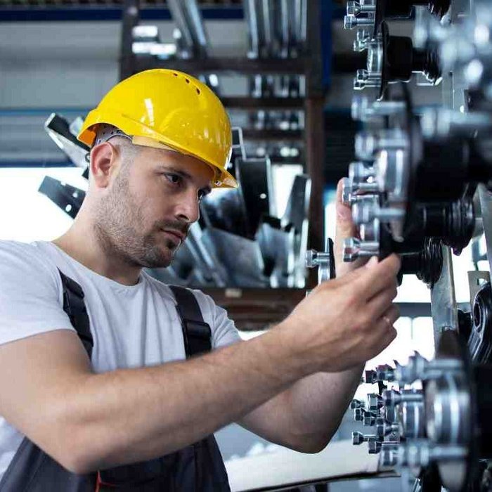 Arbeiter mit Schutzhelm und Schutzbrille bei der Bedienung oder Inspektion einer Industriemaschine