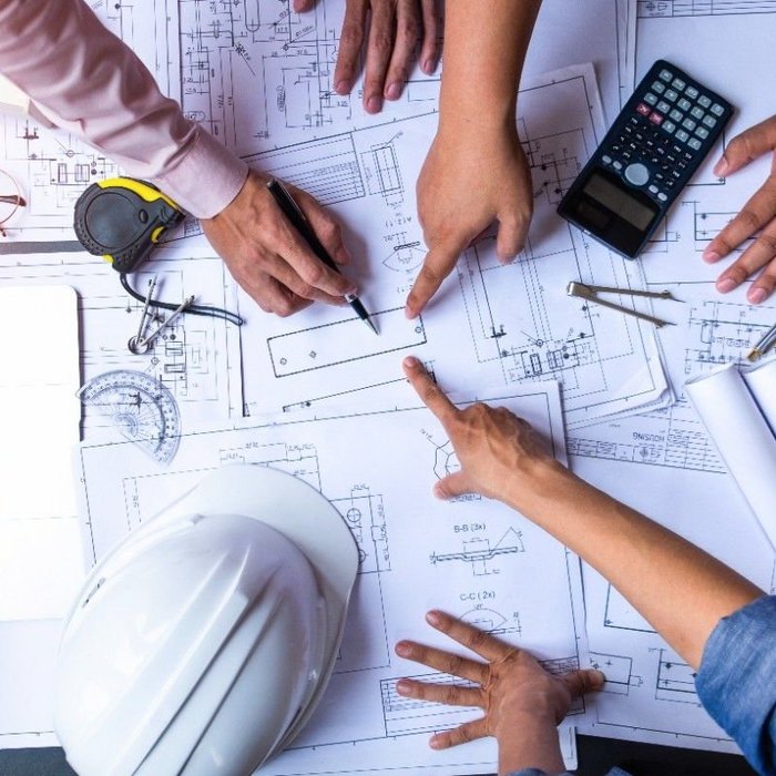 engineers pointing to building on blueprint