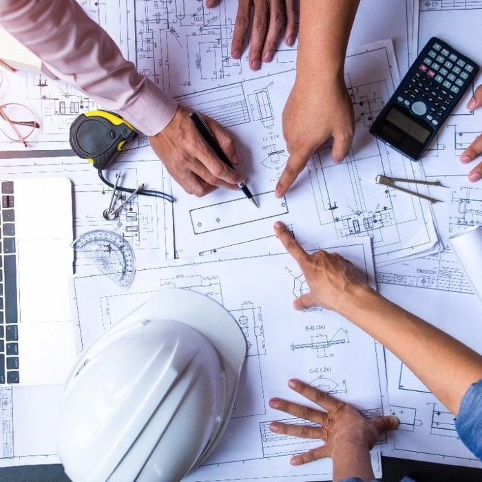 engineers pointing to building on blueprint